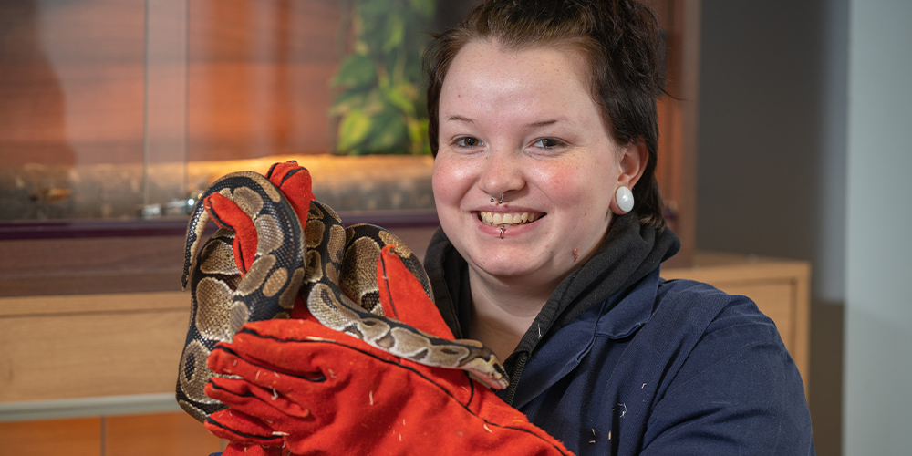 Female animal care learner holding a snake